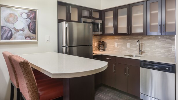 A modern kitchen with dark cabinets, stainless steel appliances, and a white countertop. - Staybridge Suites Houston I-10 West-beltway 8 by IHG (Houston)