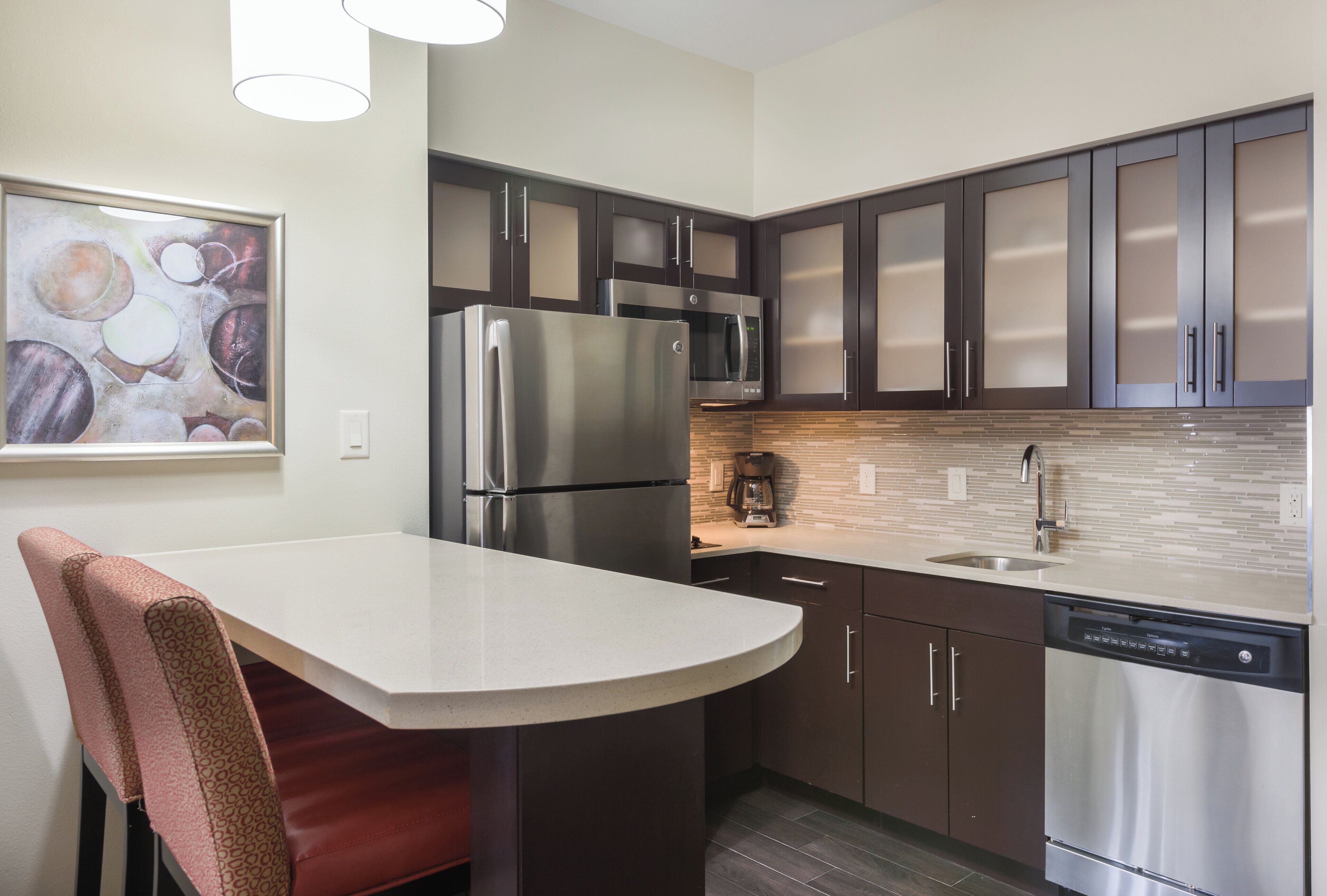 A modern kitchen with stainless steel appliances, dark cabinetry, and a tiled backsplash.