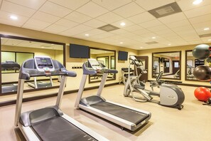 Academia com esteiras, elípticos e bolas de exercício.