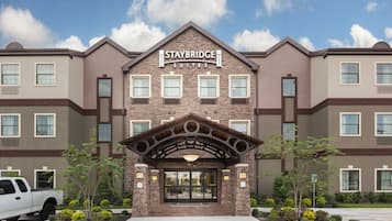 Un hotel Staybridge Suites con fachada de piedra, múltiples ventanas y un acceso cubierto.