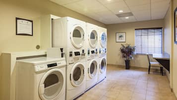 A laundry facility with multiple washing machines, a table, and a potted plant.