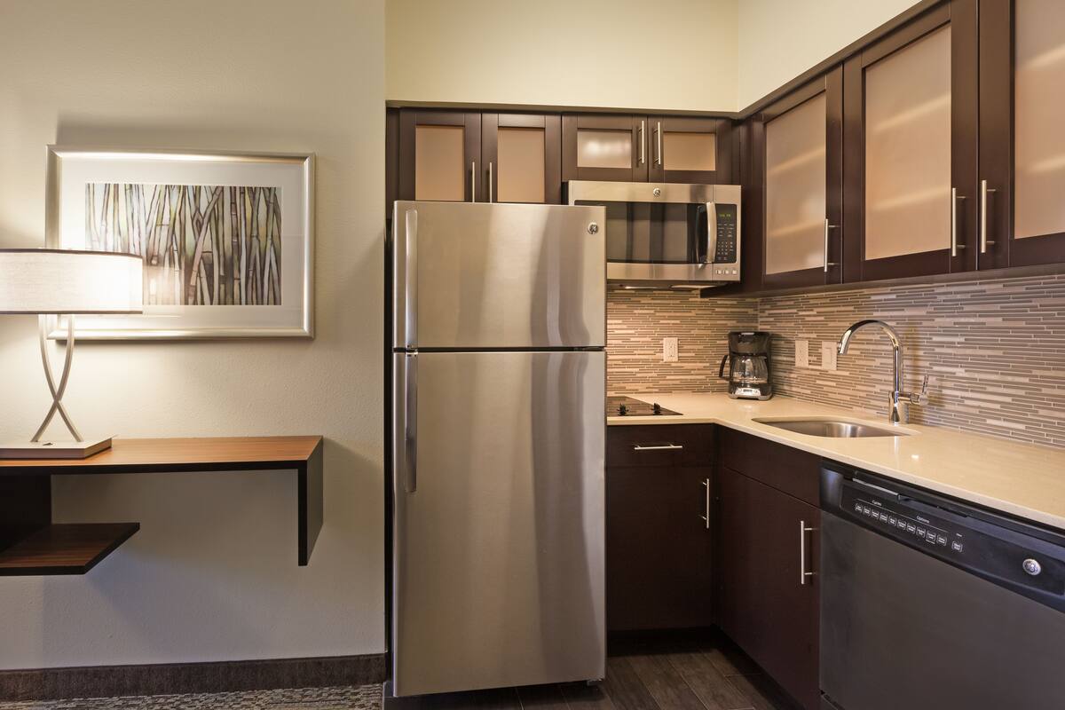 Una cocina moderna con un refrigerador de acero inoxidable, un microondas y un lavavajillas.