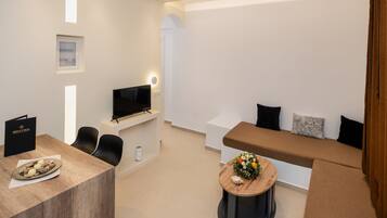 Uma sala de estar moderna com um sofá, uma TV, uma mesa de centro com flores e uma área de jantar com mesa e cadeiras.