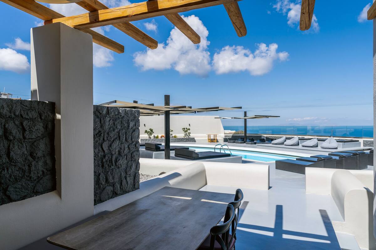 A rooftop terrace with a pool, seating areas, and a table.