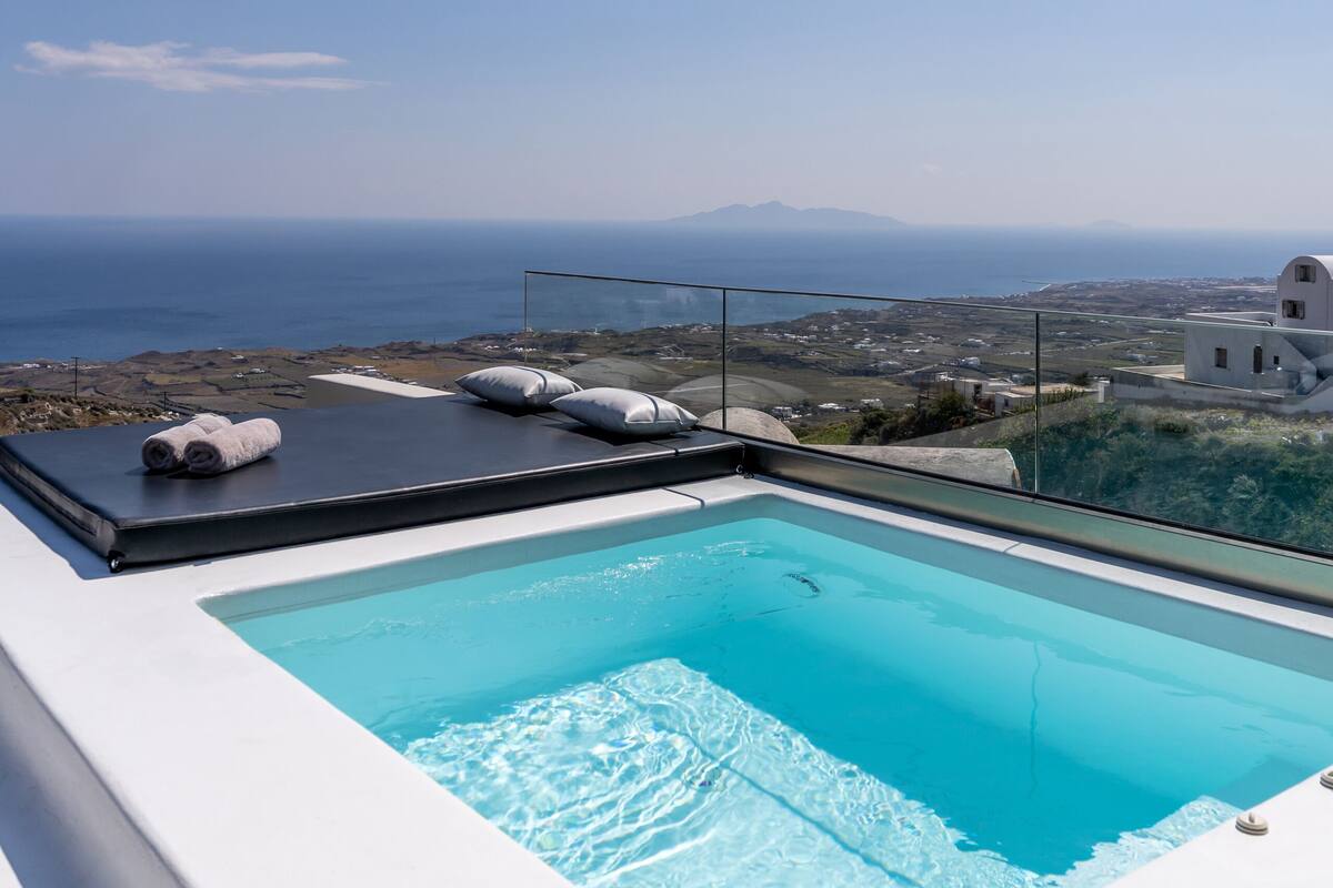 A rooftop infinity pool with a clear view of the sea and distant mountains.
