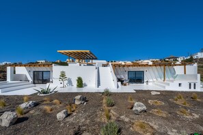 A modern house with a flat roof, large windows, and a staircase leading to a covered outdoor area. - Abrazo Villas (Santorini)
