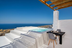 Un espace extérieur moderne, aménagé avec des sièges et une piscine, offrant une vue sur un paysage côtier.