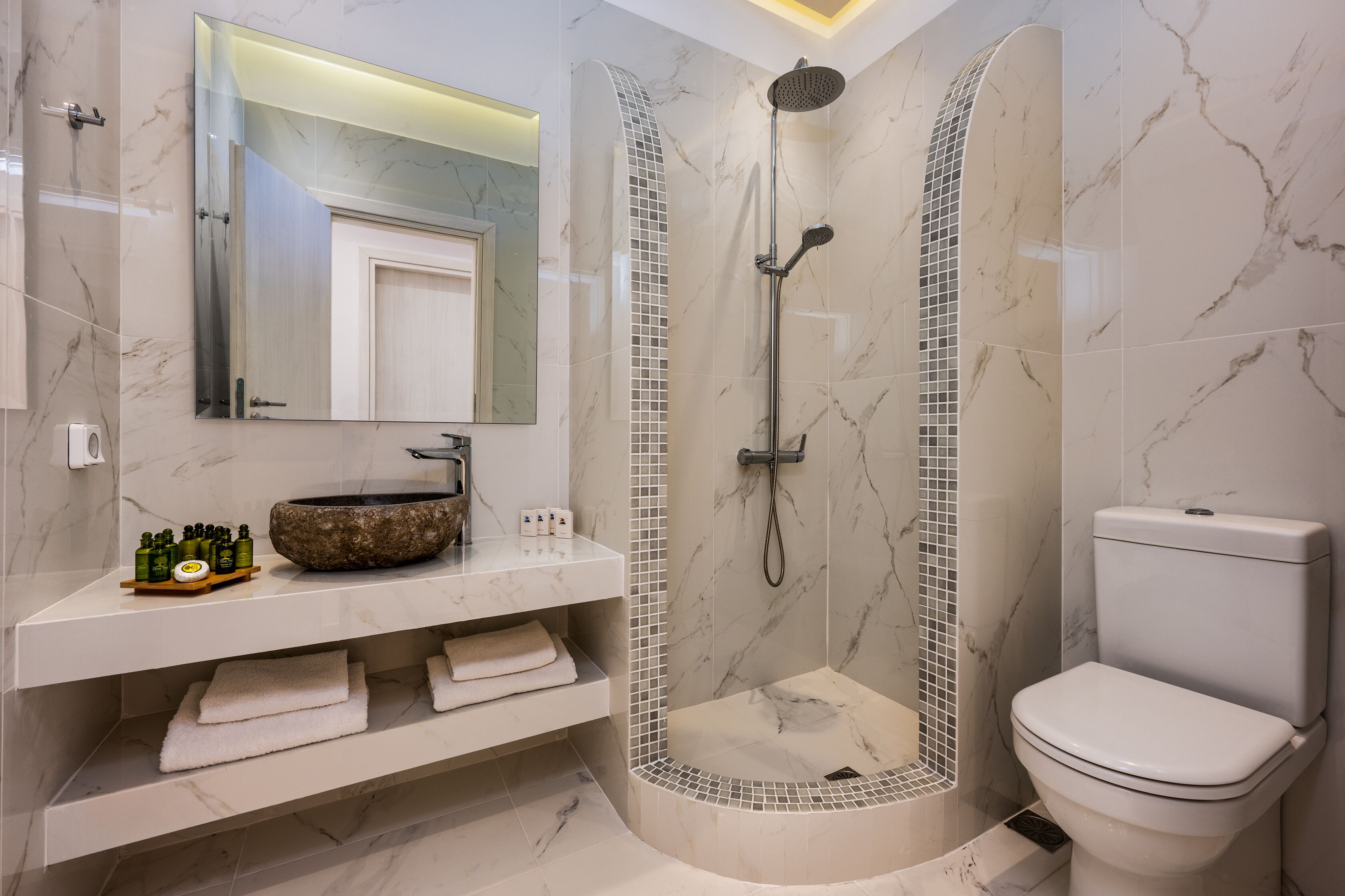 Une salle de bain moderne avec une douche à la forme arrondie, un lavabo en marbre et des toilettes.