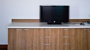 Una habitación con un armario de madera, un televisor de pantalla plana, aire acondicionado y una lámpara decorativa en el techo.
