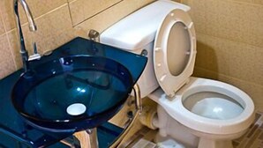 Un baño con lavamanos de vidrio, inodoro y espejo.