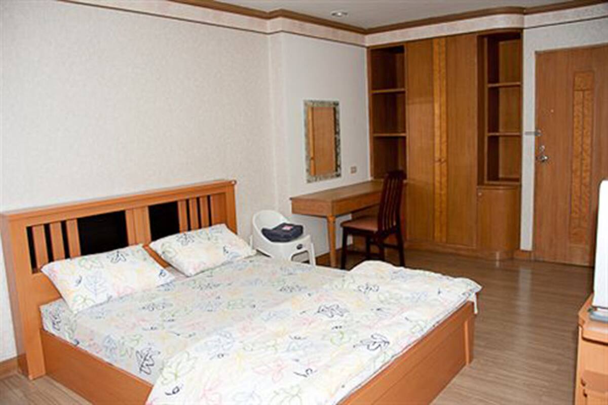 A bedroom with a bed, a desk, a chair, and a wardrobe.