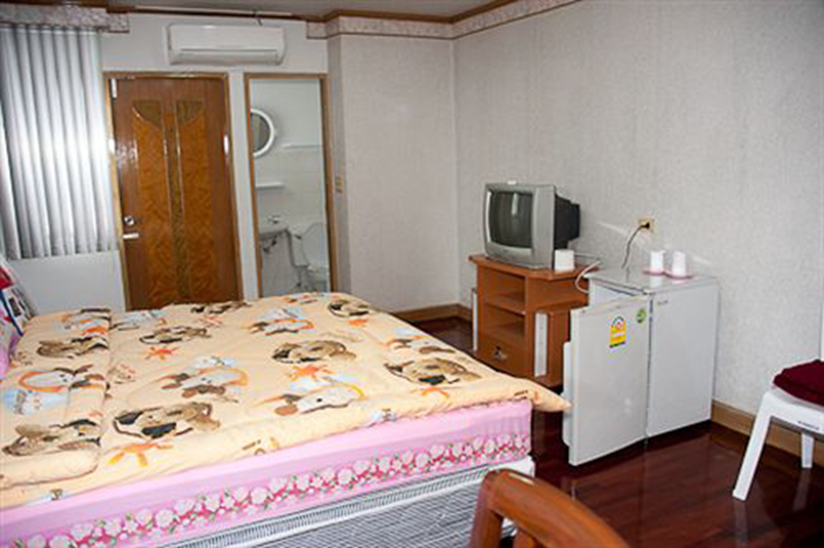 Ett hotellrum med en säng, en tv, ett kylskåp och ett badrum.