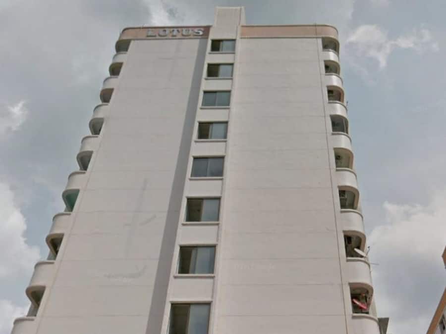 Un edificio moderno e slanciato con la scritta "LOTUS" sulla sommità. Presenta diversi balconi e una facciata lineare.