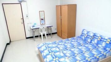 A bedroom with a bed, a desk, a chair, and a wardrobe.