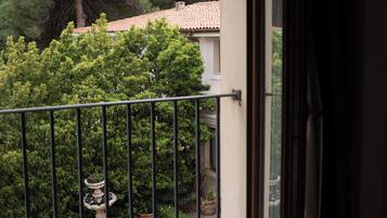 Un balcón con vistas a un jardín, un tejado de tejas y un árbol.