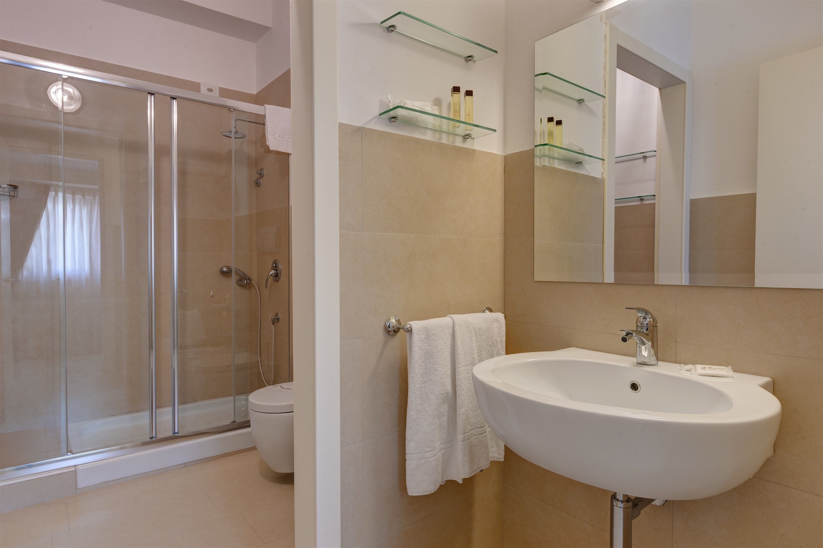 Un baño moderno con cabina de ducha de vidrio, un lavamanos blanco y un espejo sobre él.