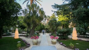 A pathway leading through a garden with large planters and tall conical lights. - Hotel Parco delle Fontane (Syracuse)
