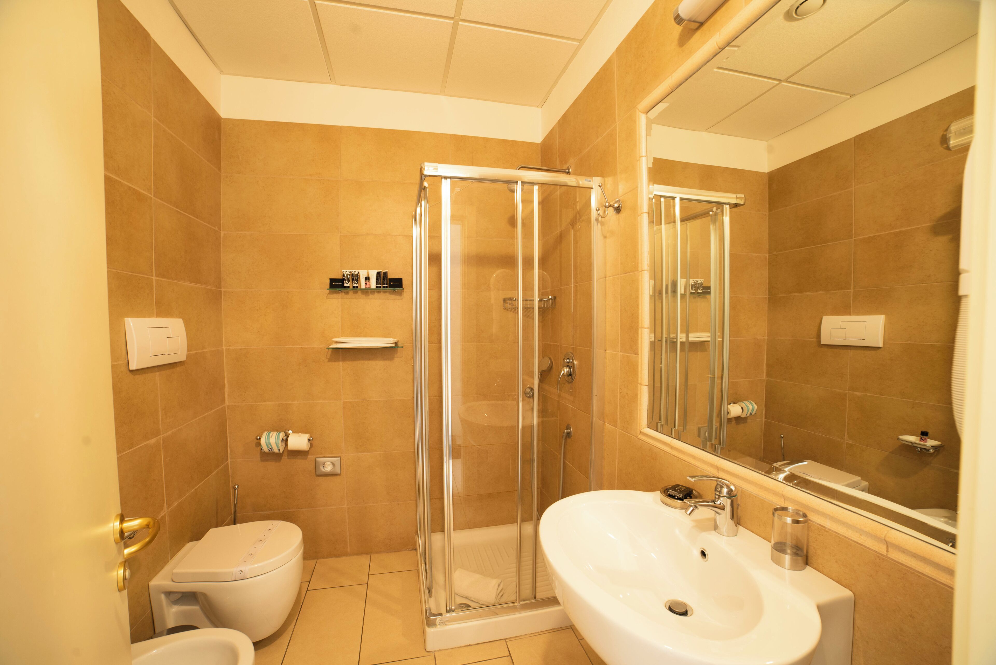 A bathroom with a glass-enclosed shower, a white sink, and a toilet.