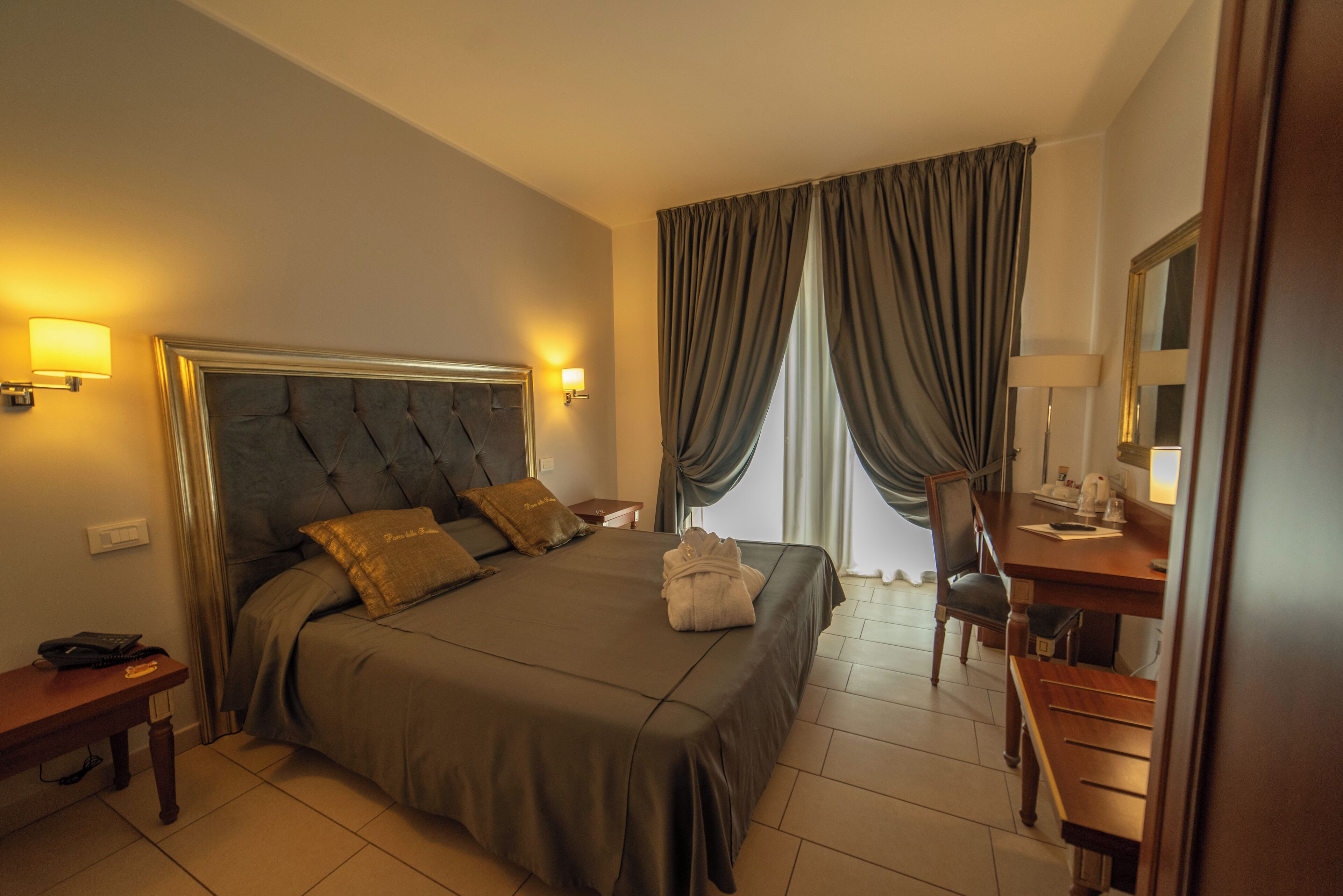 A hotel room with a large bed, bedside tables, a desk, and a chair.