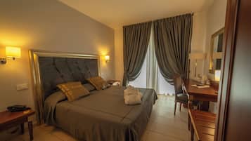 Una habitación de hotel con una cama grande, mesitas de noche, un escritorio y una silla.