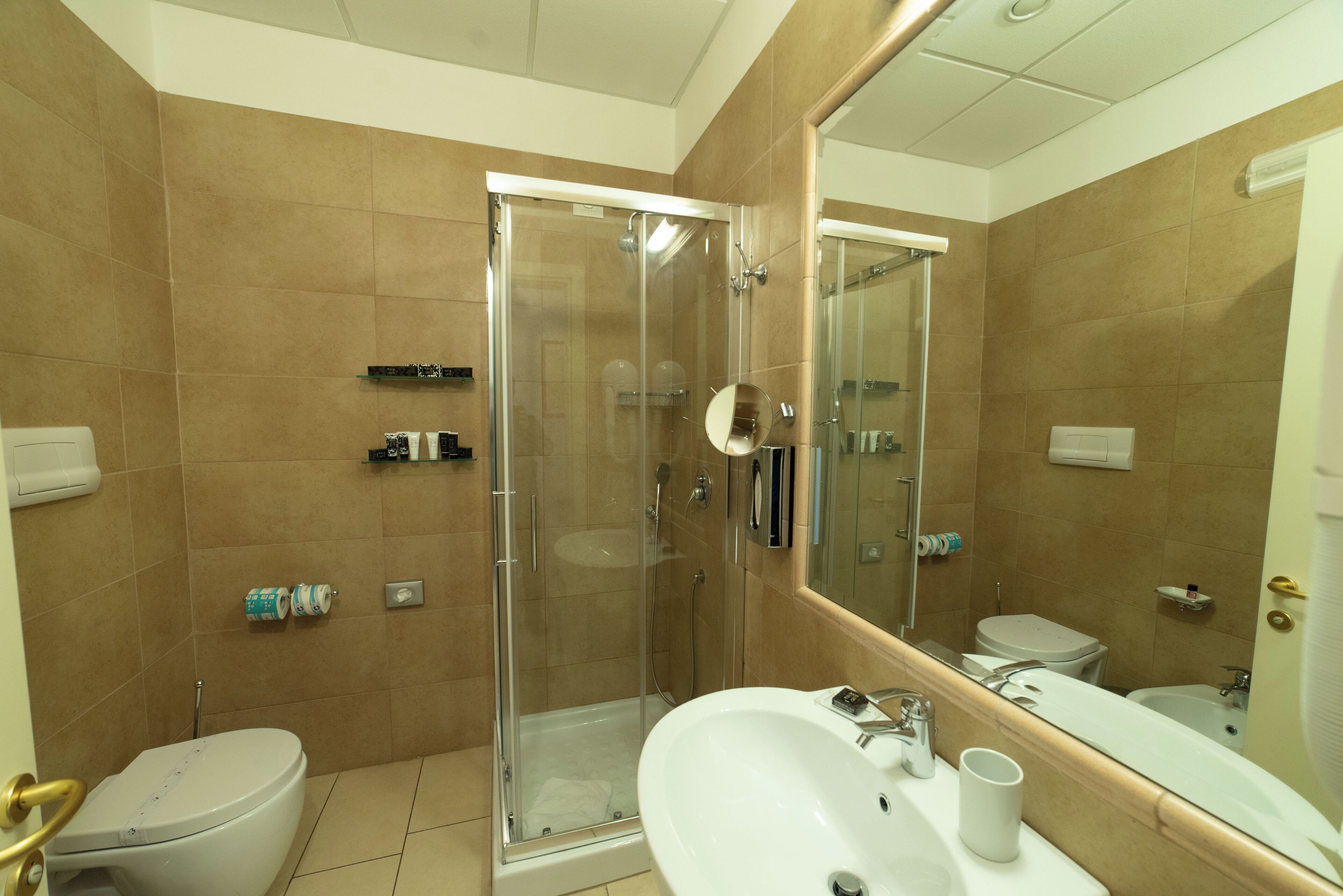 Un baño moderno con ducha de vidrio, un lavabo blanco y un espejo grande.