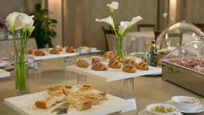 A buffet with various food items, including pastries and a meat display, in a well-lit room with a neutral color scheme. - Hotel Parco delle Fontane (Syracuse)