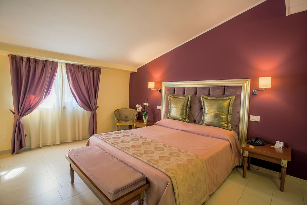 A hotel room with a large bed, a bedside table, a nightstand, and a chair.