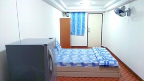 A small, single-room apartment with a bed, a washing machine, a wardrobe, and a door. - SB Apartment (Bangkok)