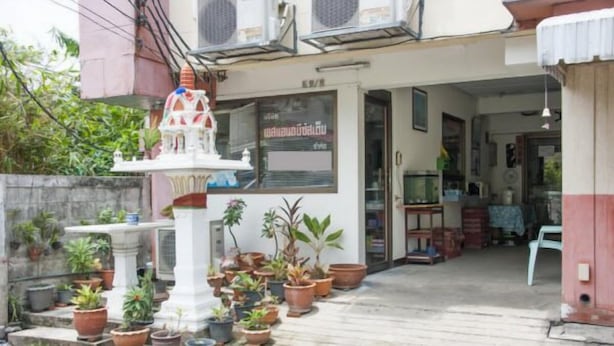 A building with a white facade, multiple air conditioning units, and a variety of potted plants in front. - SB Apartment (Bangkok)