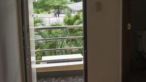 A room with a balcony, a door, and a view of greenery outside. - SB Apartment (Bangkok)