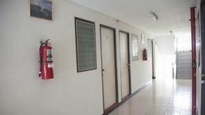 A corridor with doors, a fire extinguisher, and a staircase. - SB Apartment (Bangkok)