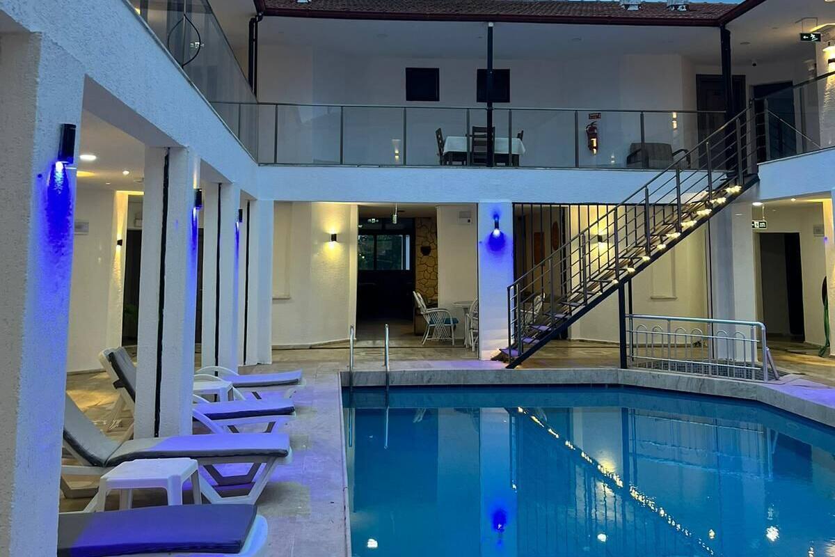 A pool area with lounge chairs, a staircase, and a glass balustrade.