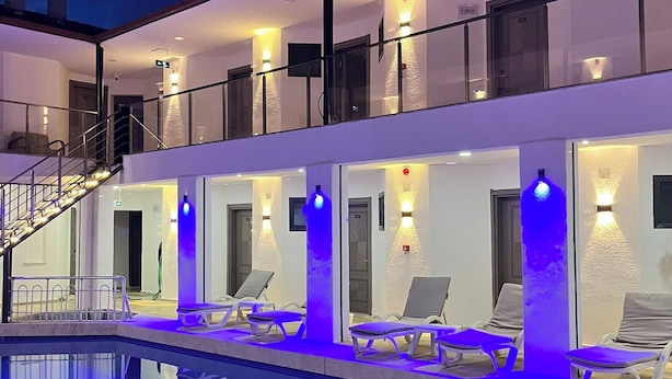 A modern hotel with a pool, lounge chairs, and a staircase leading to the upper floor. - Han Dalyan Hotel (Ortaca)