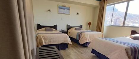 Habitación de hotel con dos camas, una mesita y una ventana con vista a la ciudad.