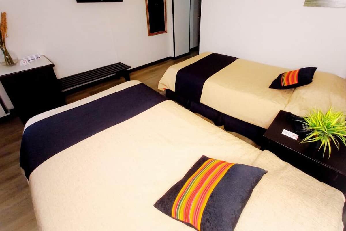 A hotel room with two beds, a small table with a plant, and a nightstand.