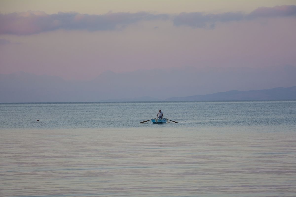 A calm sea with a single boat carrying a person.