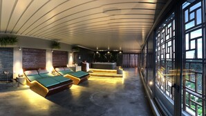 A modern spa area with a stone wall, a sofa, and two massage tables.