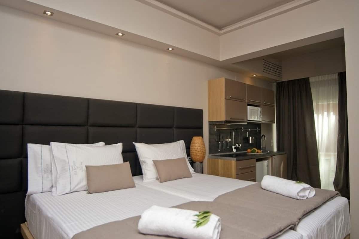 A hotel room with a large bed, a kitchenette, and a view of the city.