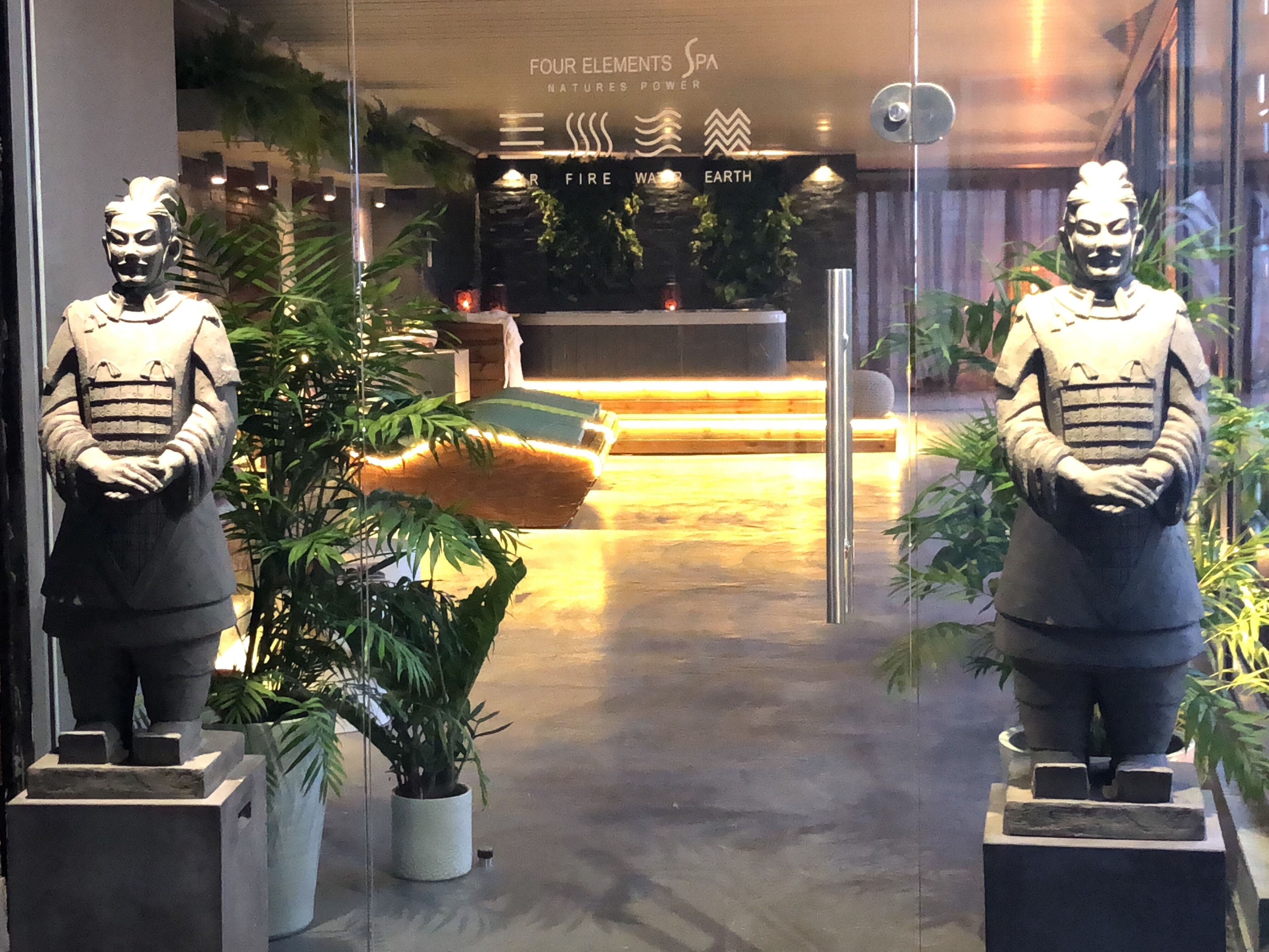 A reception area with two stone statues, a reception desk, and a potted plant.