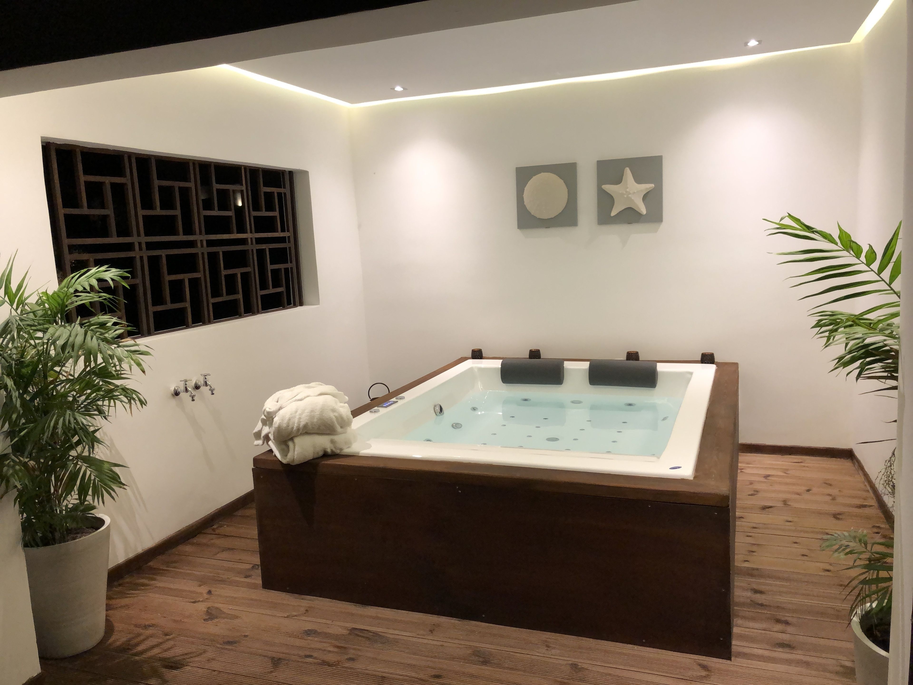 A modern bathroom with a freestanding bathtub, a window with a grid pattern, and two wall-mounted decorative items.