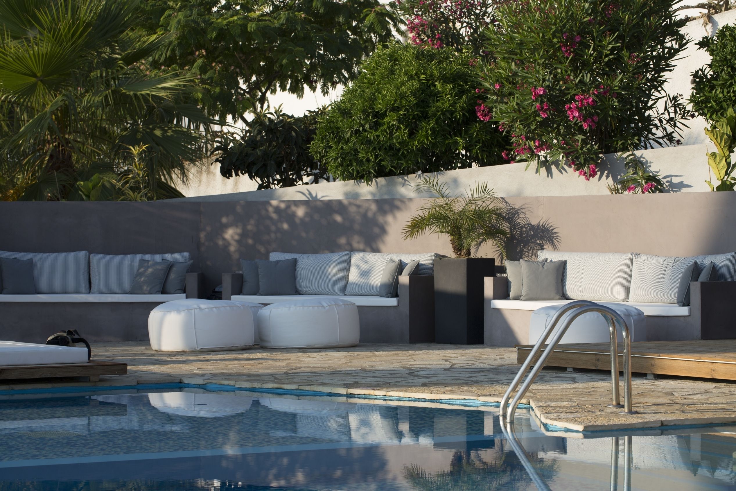 A modern outdoor pool area with a seating area, a pool, and surrounding greenery.
