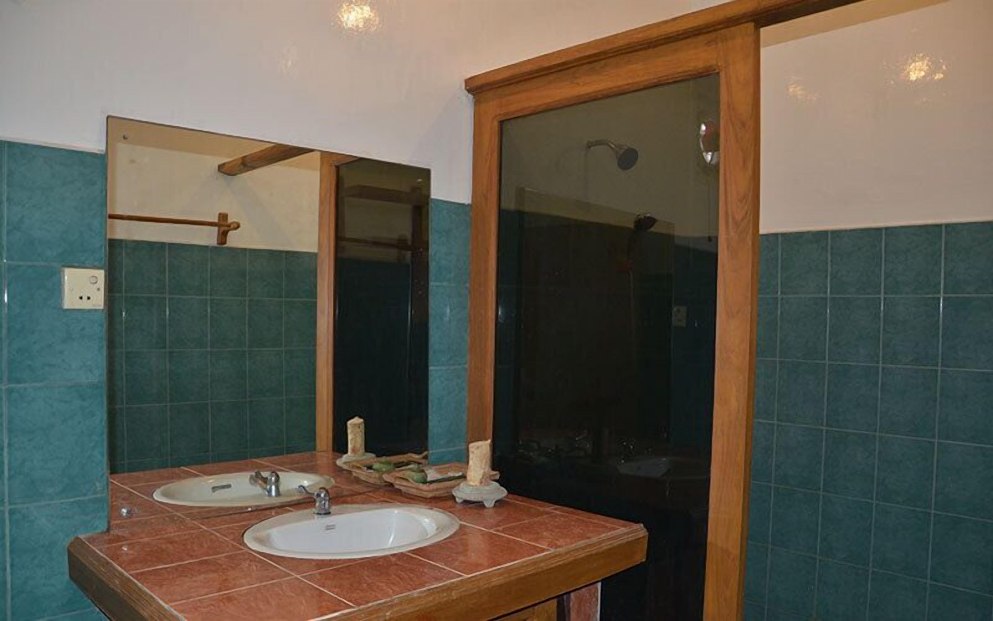 Un bany amb dues rentadores, un mirall i una dutxera.