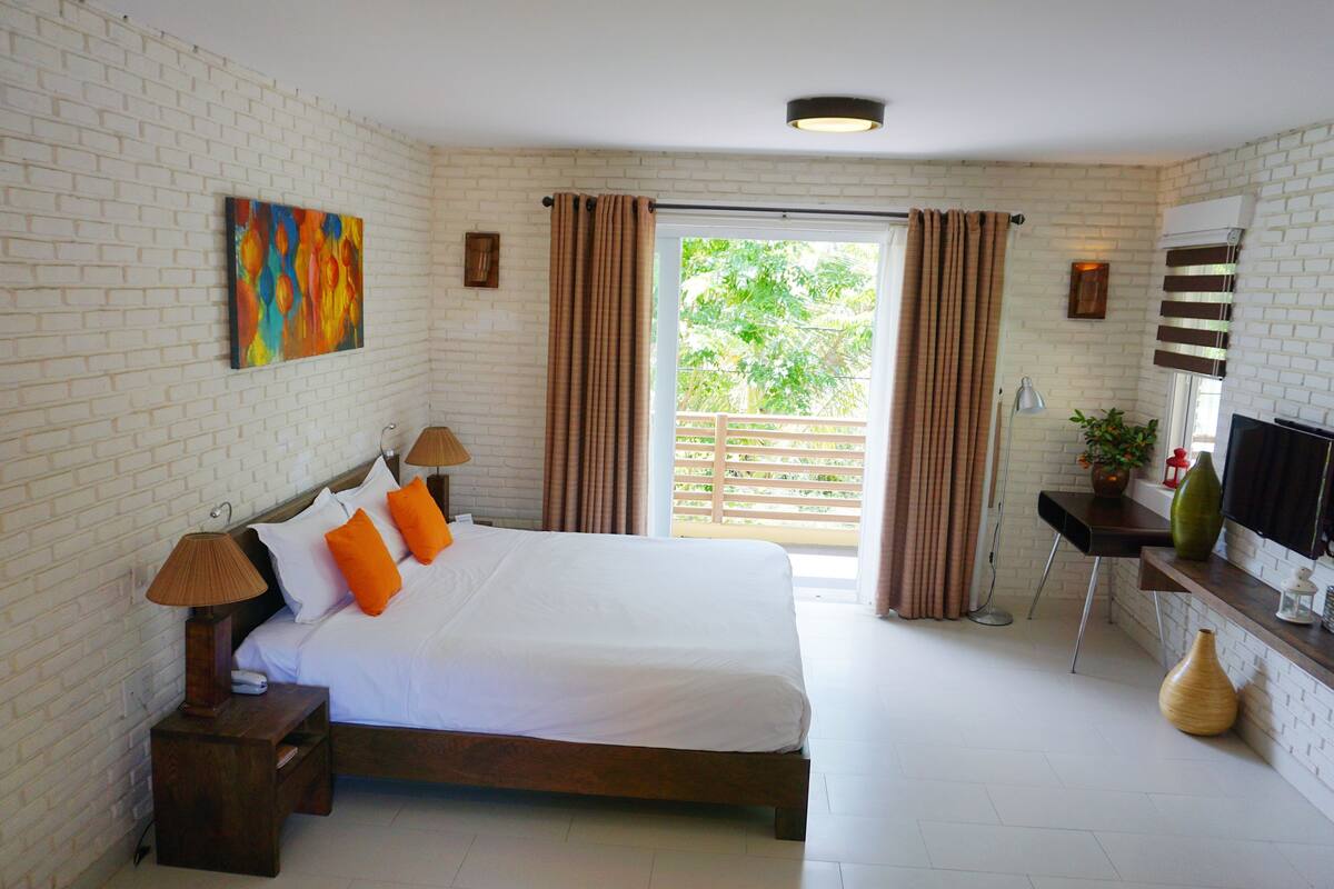 A bedroom with a large bed, a desk, and a television.
