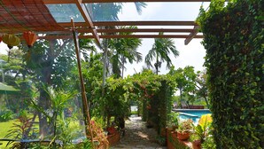 A stone pathway leading to a pool area, surrounded by lush greenery and potted plants. - Rock Villa Hoi An (Da Nang)