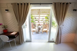 A room with a desk, chair, and a view of an outdoor patio with a table and chairs.