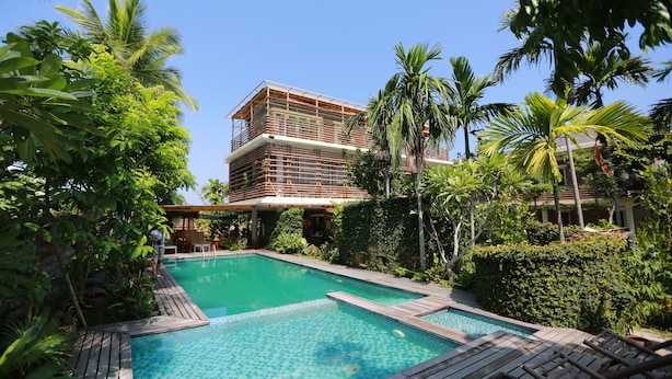 A pool area with a wooden deck, surrounded by lush greenery and palm trees. - Rock Villa Hoi An (Da Nang)