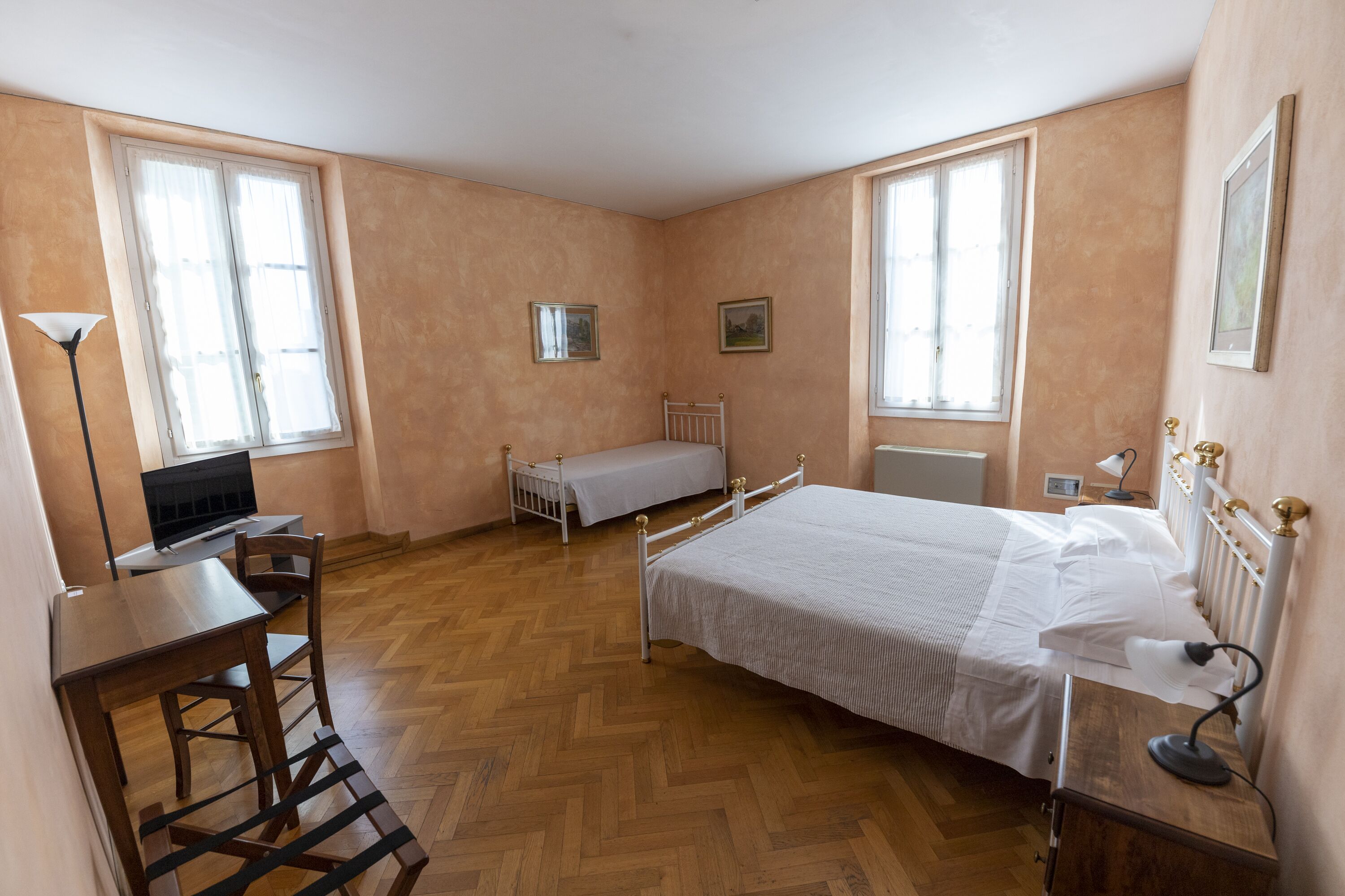 A bedroom with a bed, bedside table, lamp, and a desk with a chair.