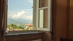 A dining table set with plates, cups, and cutlery, with a window offering a view of a mountainous landscape. - Albergo dell'Academia (Mondovi)