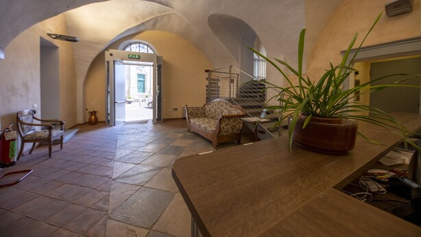 A spacious lobby with a high ceiling, arched alcoves, a reception desk, and a potted plant. - Albergo dell'Academia (Mondovi)