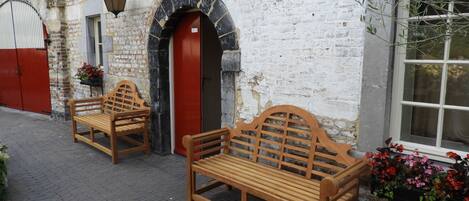 A building with a brick exterior, a red door, and two wooden benches outside.